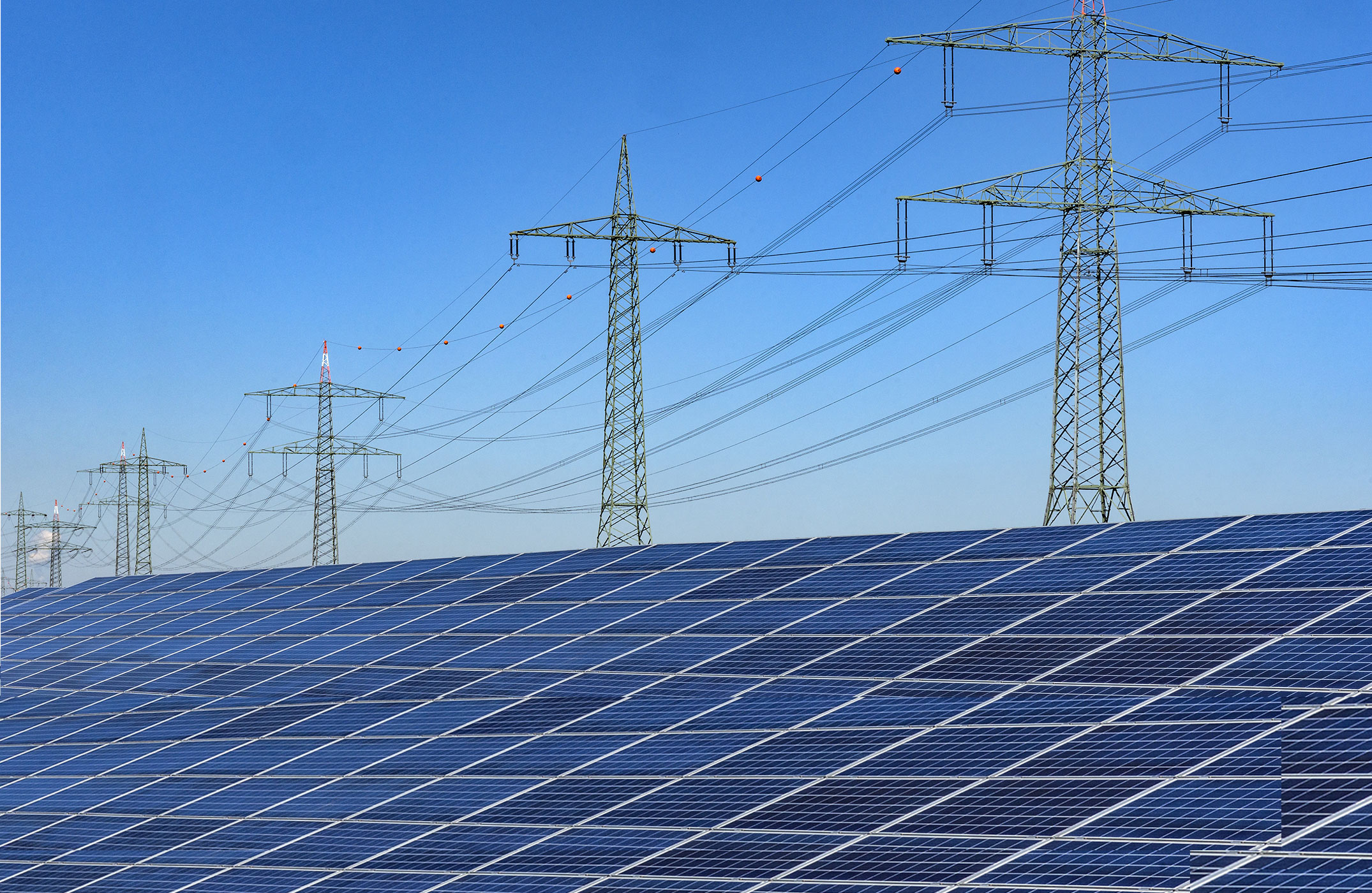 Solaranlage im Vordergrund und Strommasten im Hintergrund